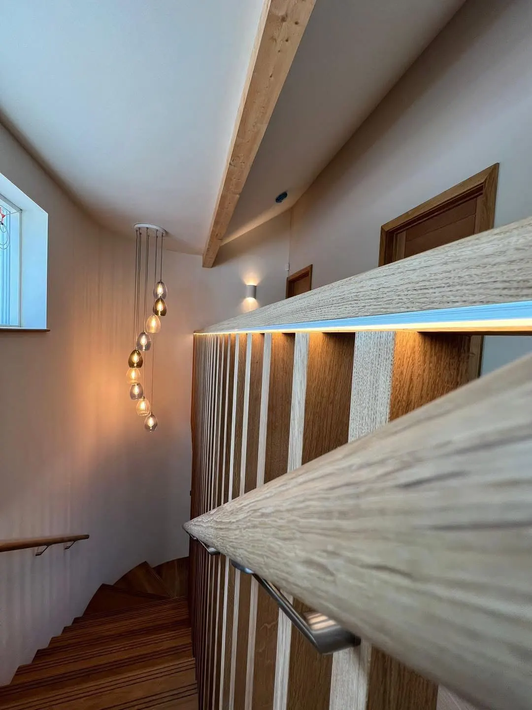 Stairwell with a cluster pendant and lit handrail